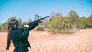 Lady shooting shells with a shotgun